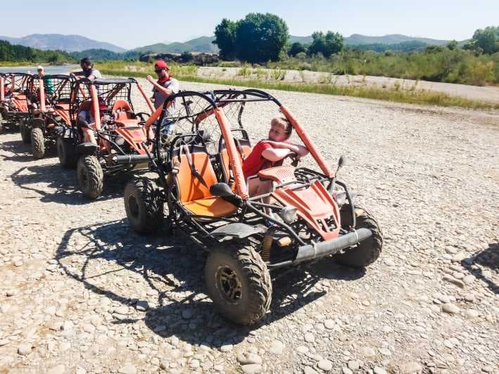 A two-seater UTV buggy splashing through mud on a rugged forest track.