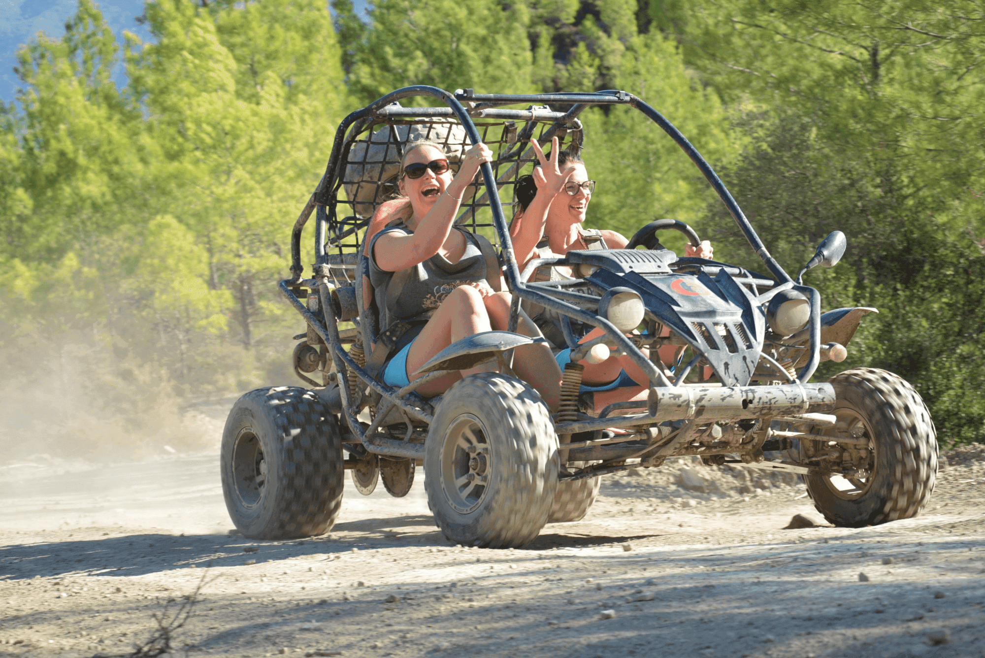 A two-seater UTV buggy splashing through mud on a rugged forest track.