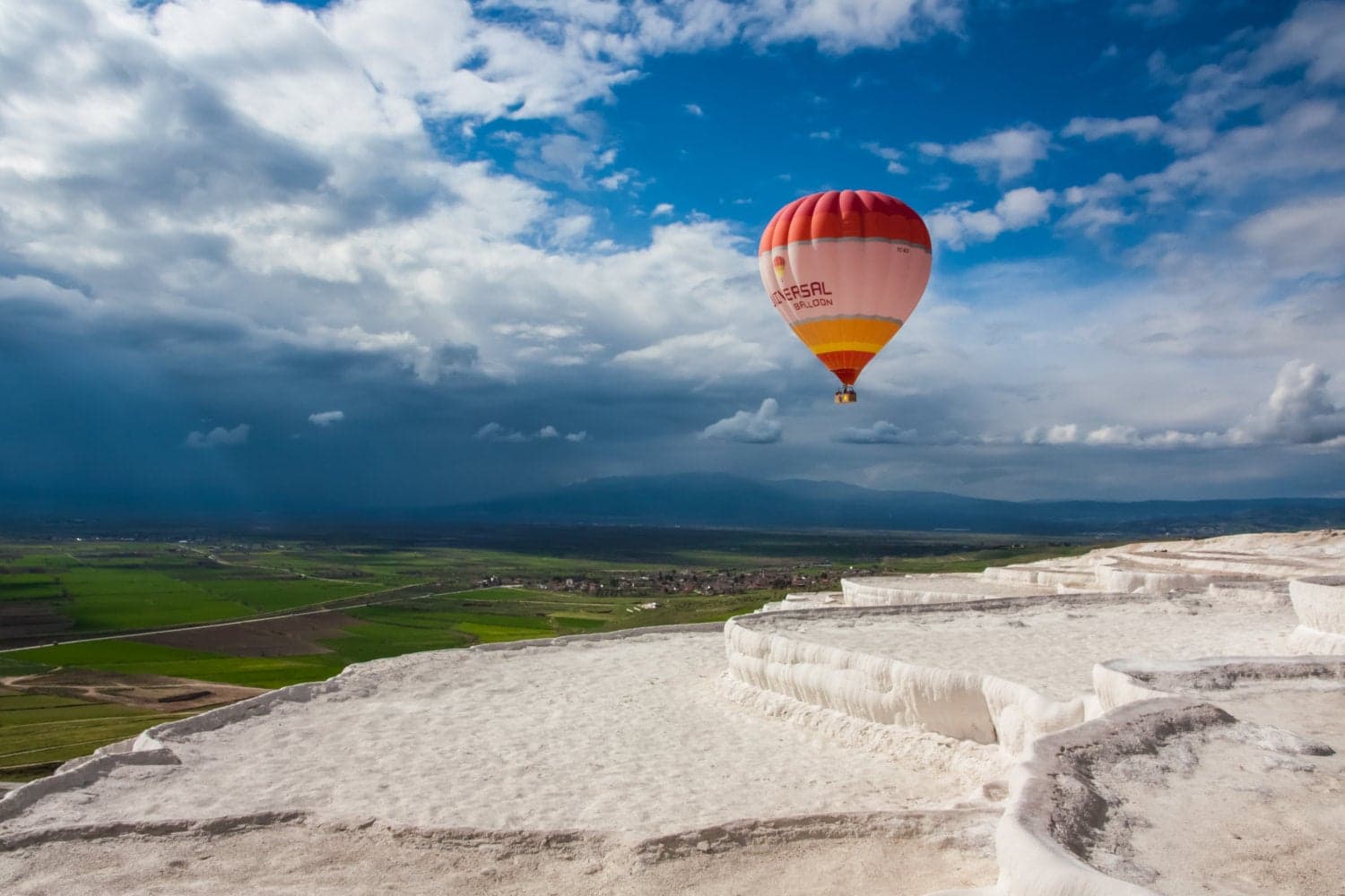 Snow-white travertine terraces of Pamukkale cascading down the hillside under a clear blue sky.